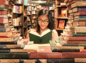 Girl reading a book surrounded by other books